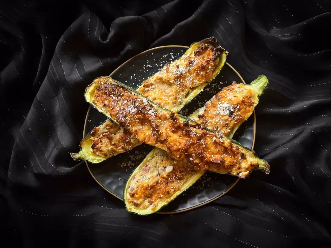 Three large zucchini halves, cut lengthwise, are stuffed with ricotta, turkey bacon, and Parmesan.