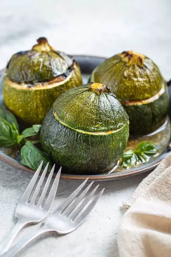 Arranged on a plate, three zucchinis hollowed out of their flesh are filled with the vegetarian stuffing.
