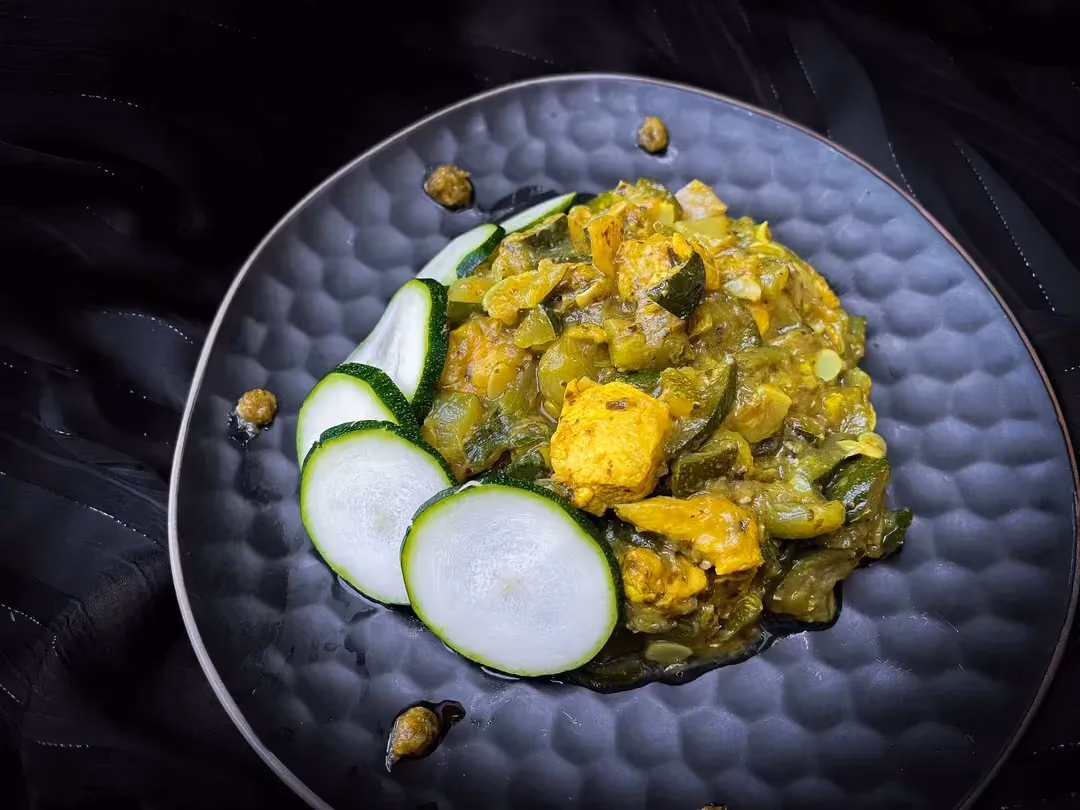 Dans un joli plat alvéolé de couleur bleu, se trouve les courgettes et le poulet enrobé de sauce Pesto. Six tranches de courgettes servent de déco.