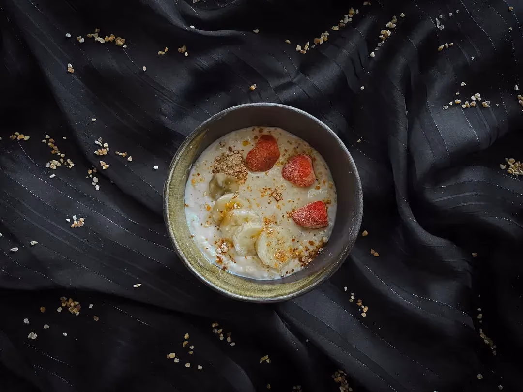 Dans un bol en grès se trouve la recette de crème protéinée à la banane et cacahuètes.