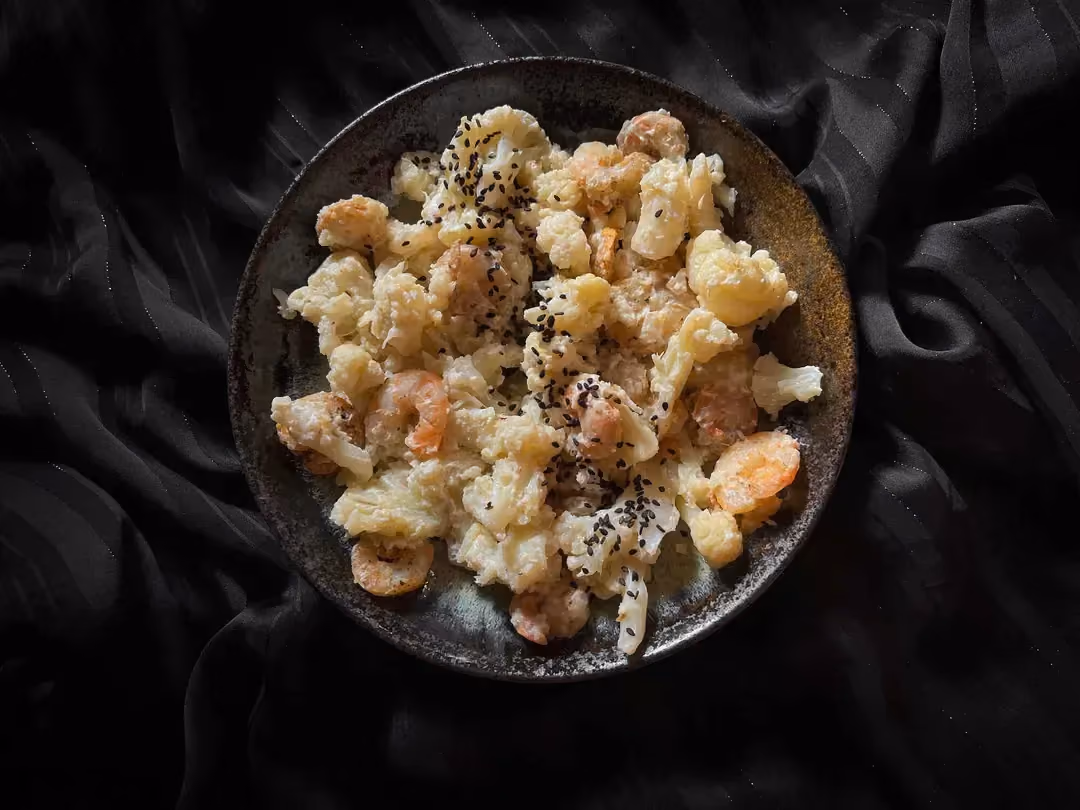 A small blue bowl holds the shrimp with cauliflower, ricotta, and honey recipe.