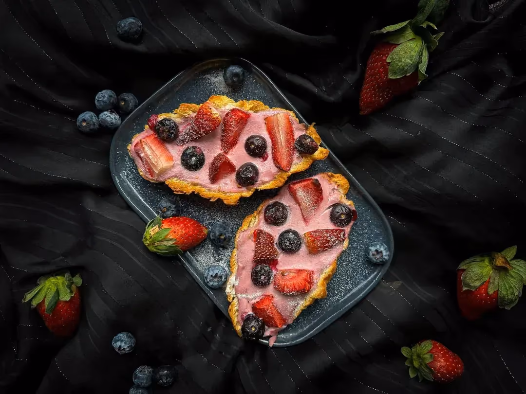 Le croissant ouvert en deux aux fruits rouges est disposé sur un plat en faïence rectangulaire peu profond. Tout autour se trouve quelques fraises.