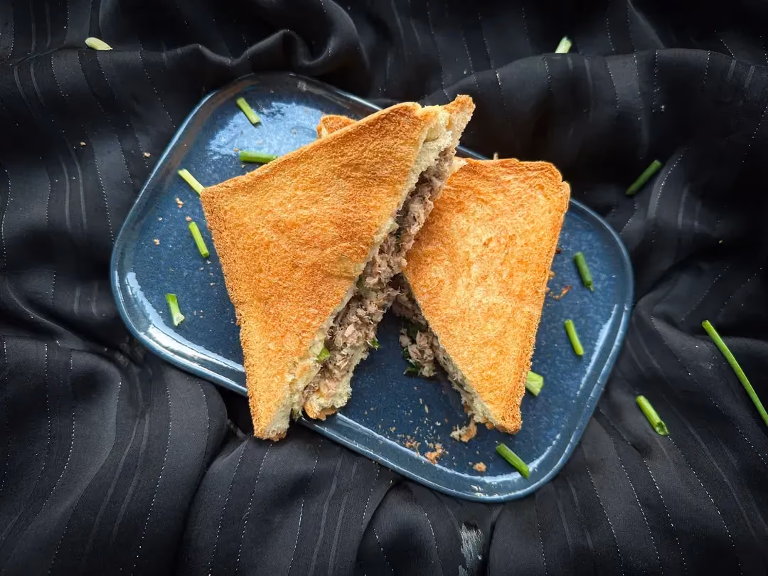Quatre sandwichs grillés au thon et au fromage à l'aspect "so british" sont déposés sur une petite desserte en bois.