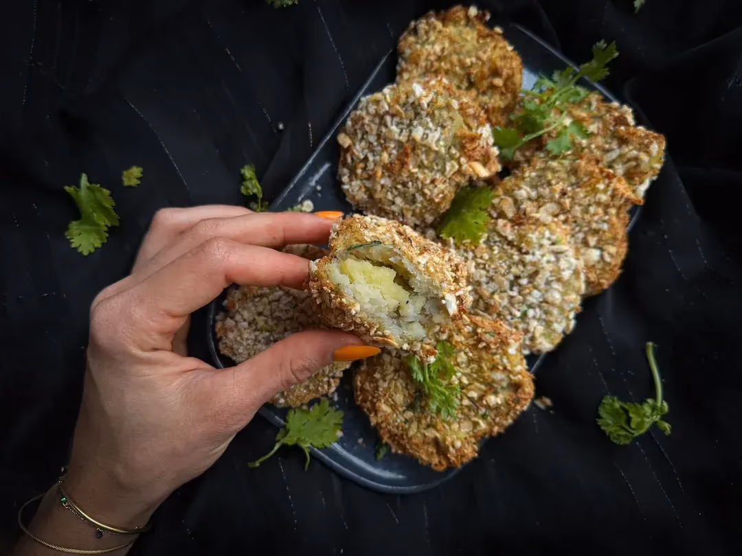 Deux grosses croquettes de cabillaud sont déposées sue une assiette de couleur blanche. Une tranche de citron jaune est présente.
