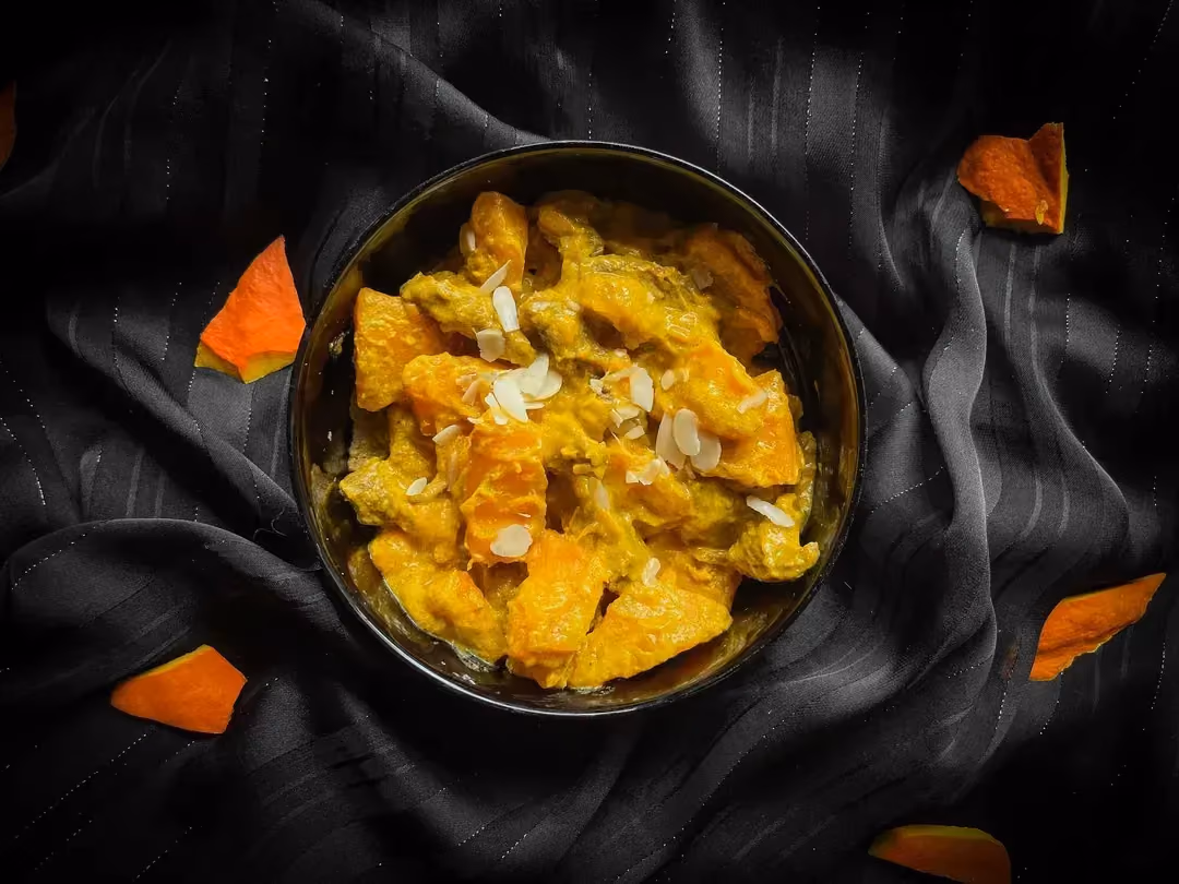 Dans un bol se trouve le curry de boeuf au lait de coco et potiron. Le curry a joliment coloré en jaune les ingrédients de la recette.
