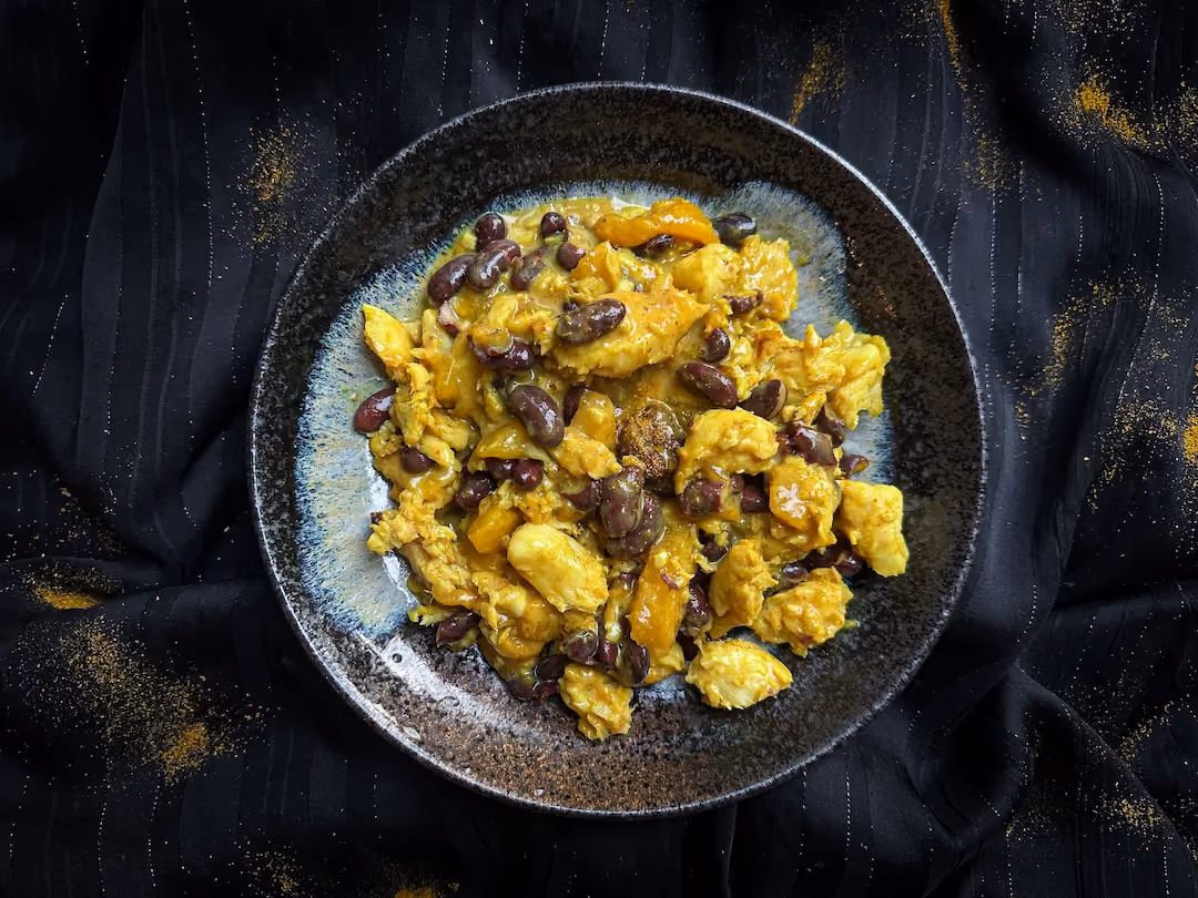 In a large bowl, on one side a big scoop of rice with four large slices of mango, and on the other side pollock with red beans.