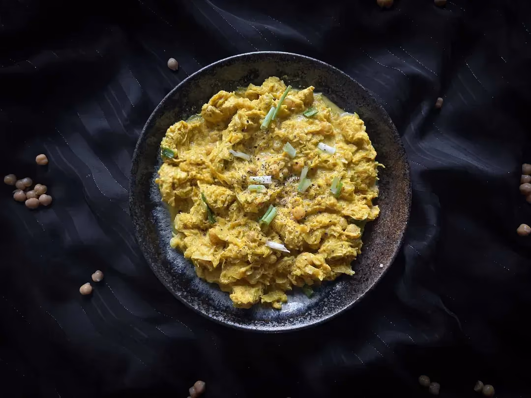 A small bowl holds the chickpea, cabbage, and chicken curry recipe. The beautiful yellow color comes from the curry powder.