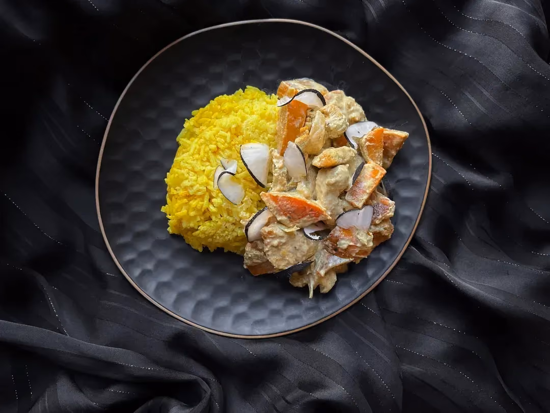 A small bowl holds the Kakis Chicken Curry, served with yellow rice.