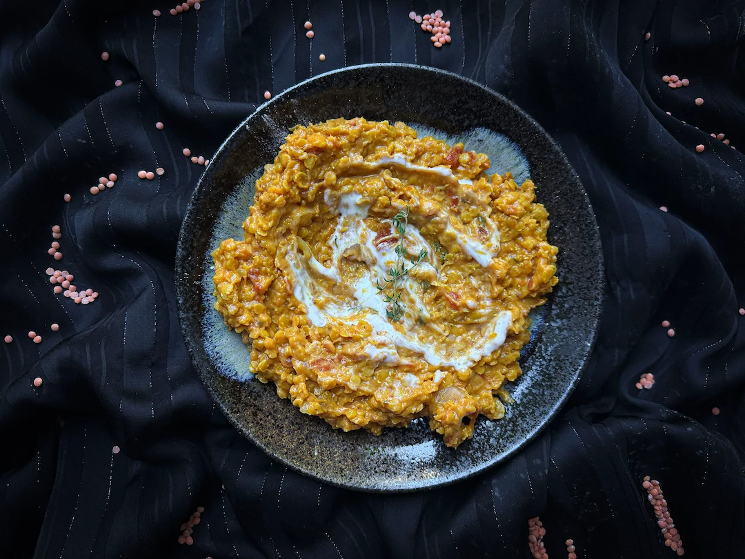 In a deep blue-and-black bowl, the red lentil dahl appears as a kind of saffron-colored purée.
