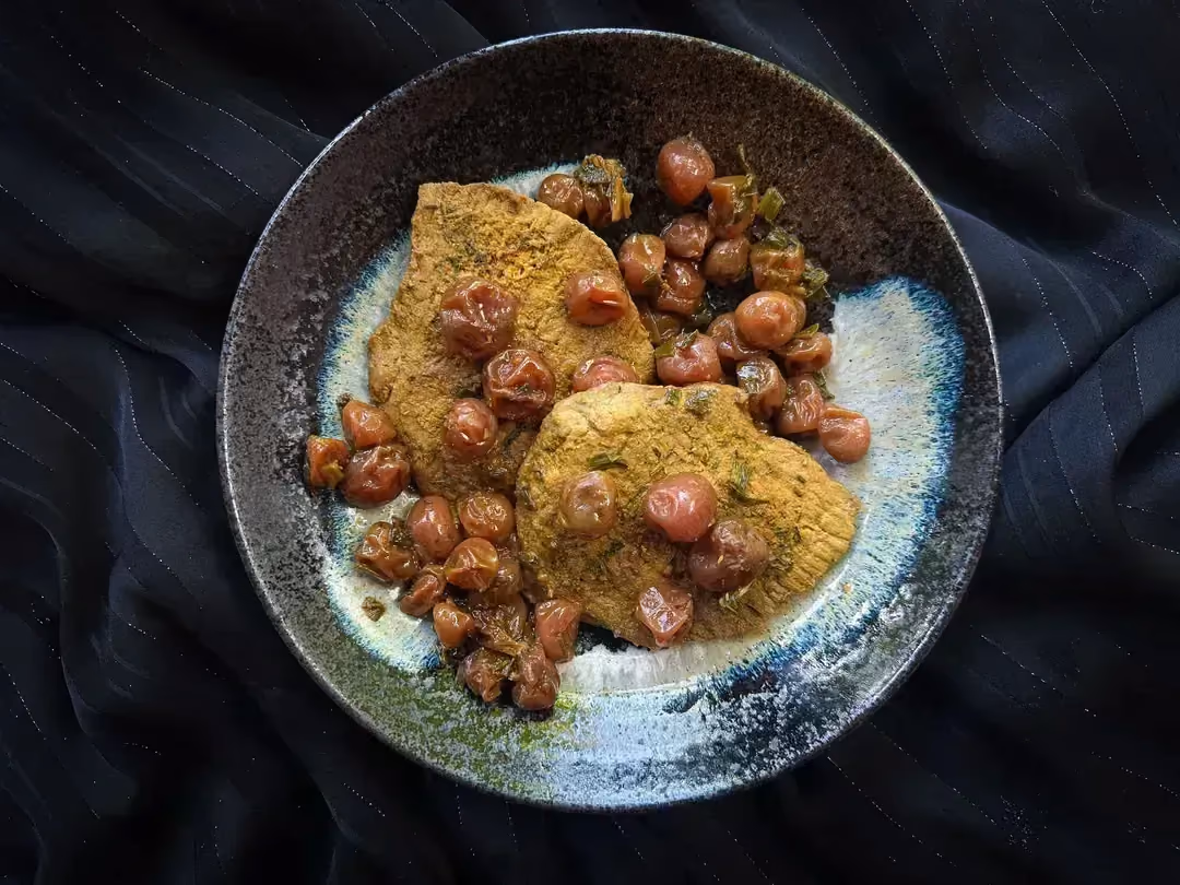 La recette d'escalopes de porc aux cerises est présentée dans un petit saladier de couleur bleu.