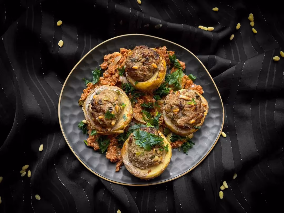 Quatre fonds d'artichauts farcis à la viande hachée de boeuf sont présentés dans un plat de couleur bleu alvéolé.