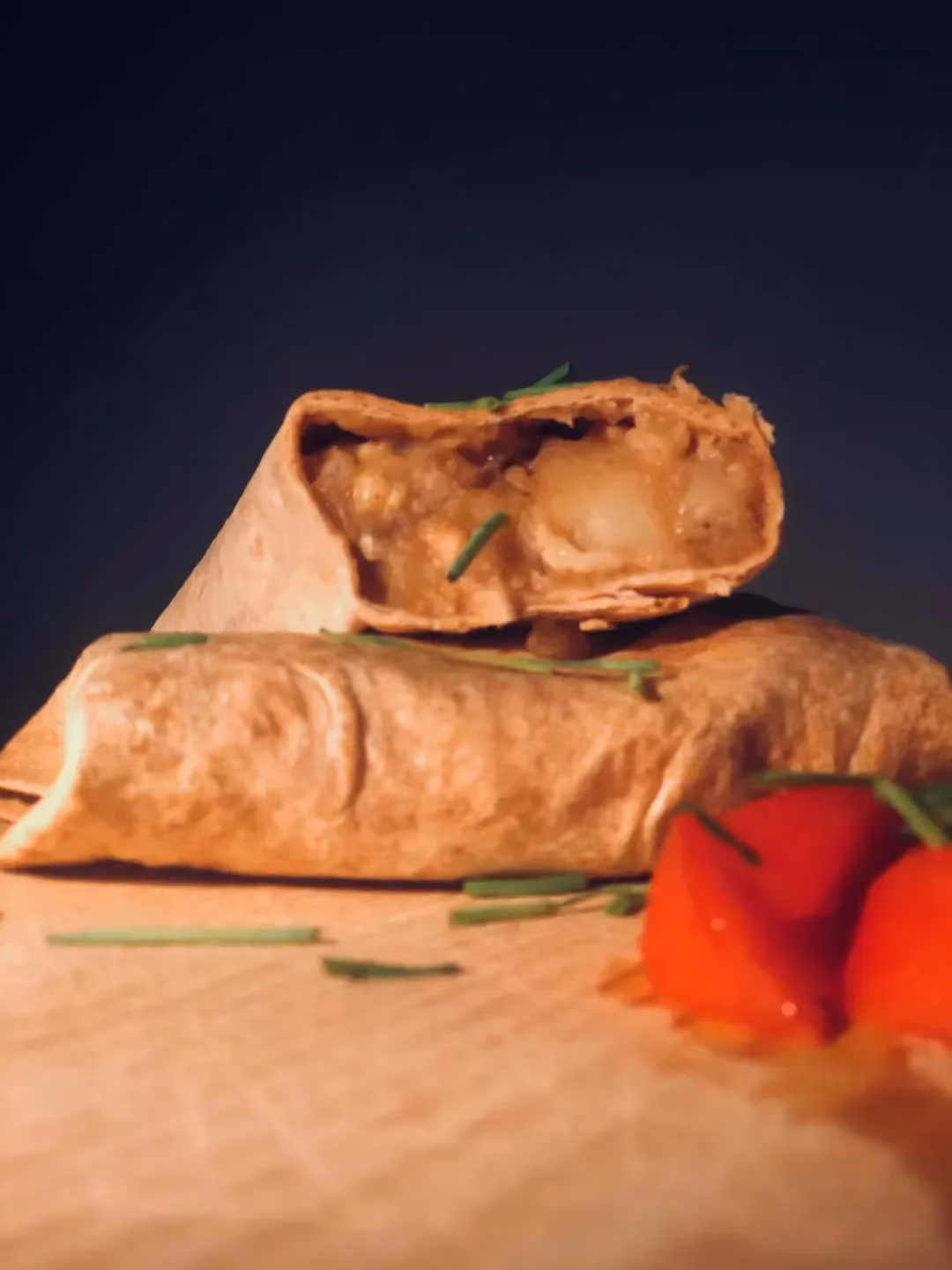 Two large mountain-style French tacos are placed on a wooden cutting board. One of them shows the generous meat filling.