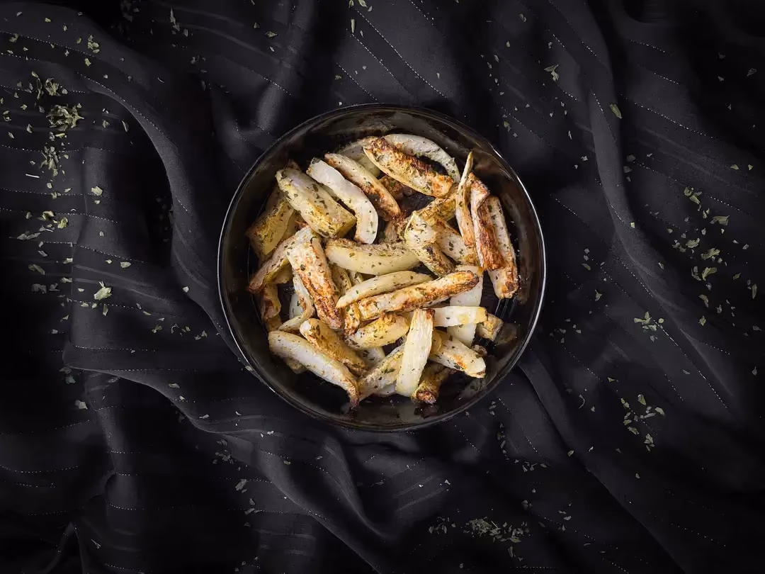 Parsnip fries with mild spices, coriander, and cumin are presented in a blue bowl.
