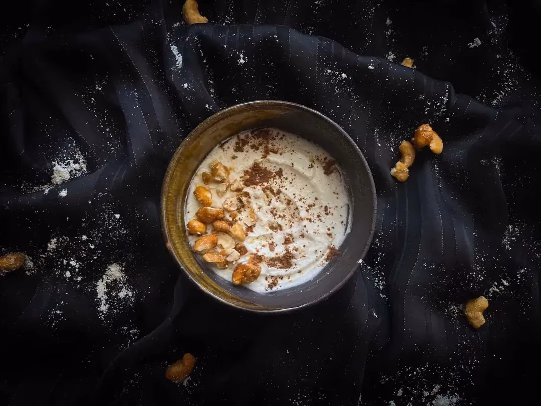 A stoneware dish holds the fromage blanc, coconut, and caramelized peanuts recipe. The caramelized peanuts make up the topping.
