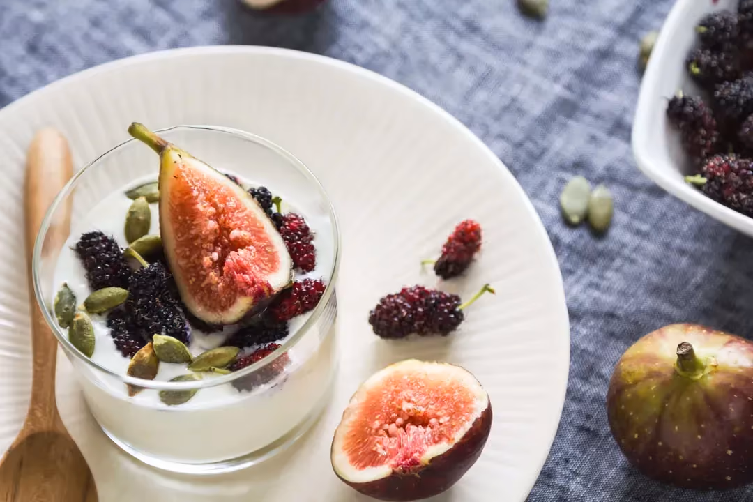 Une grande verrine contient le fromage blanc, les pistaches avec l'arôme de fleur d'oranger. Une moitié de figue est posée sur le dessus.