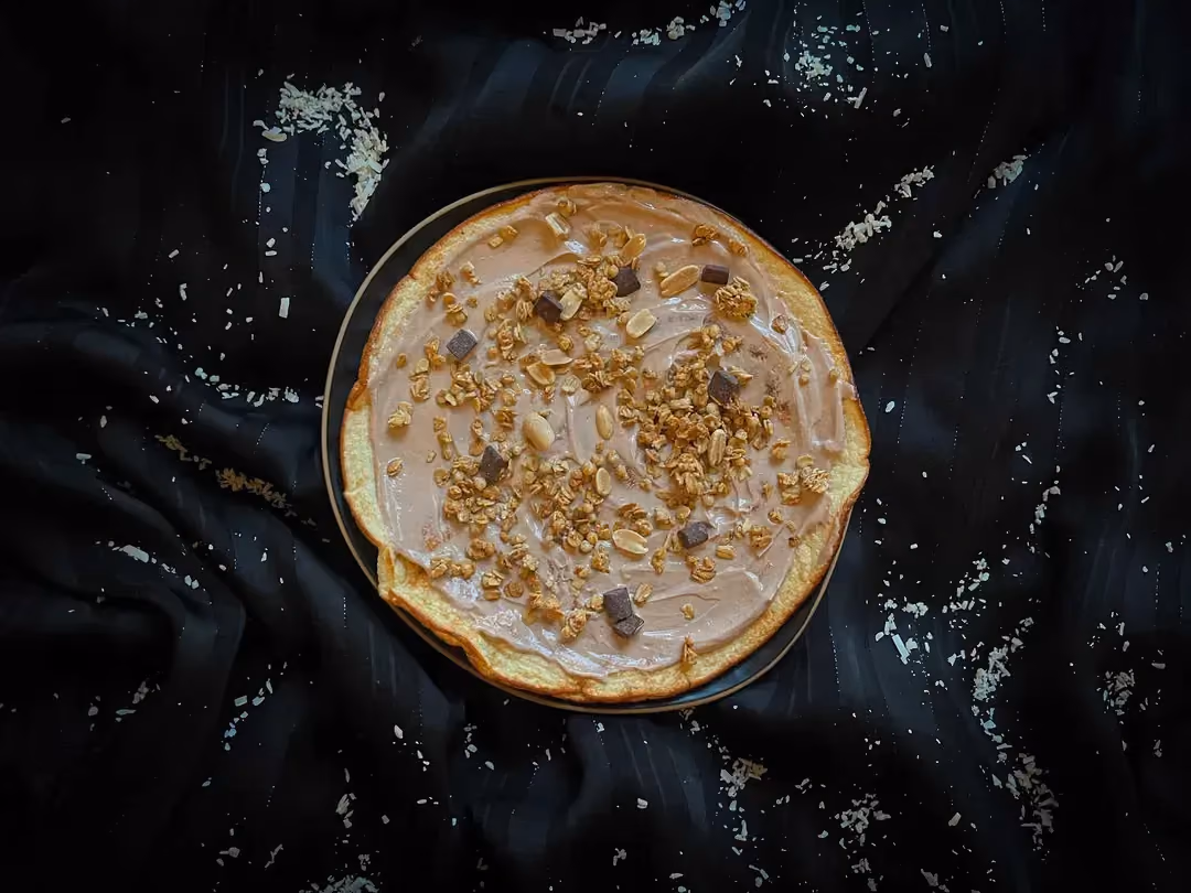 The coconut galette with peanut sauce is presented on top of a blue bowl.