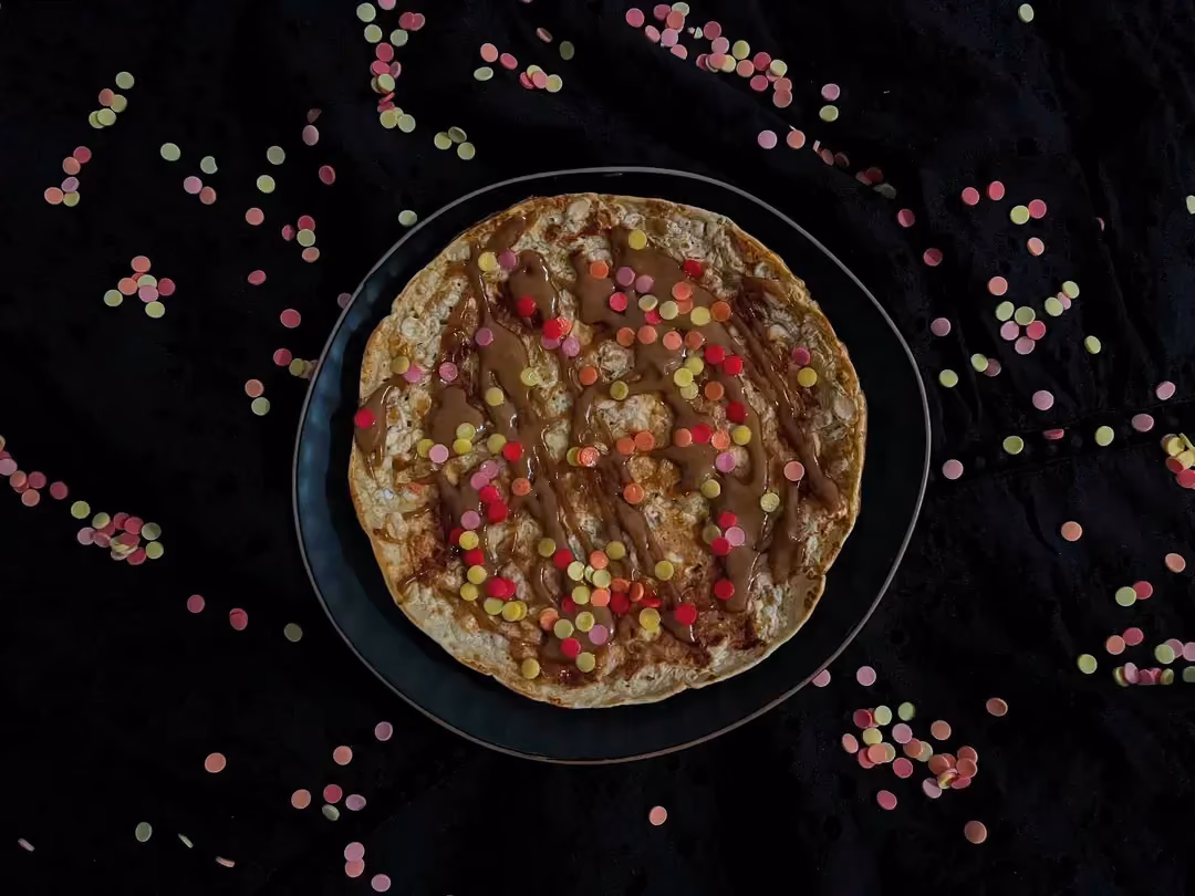 Dans un large bol se trouve la galette protéinée à l'orge et à la purée de cacahuètes. Le topping est constitué de petites lentilles de chocolat.