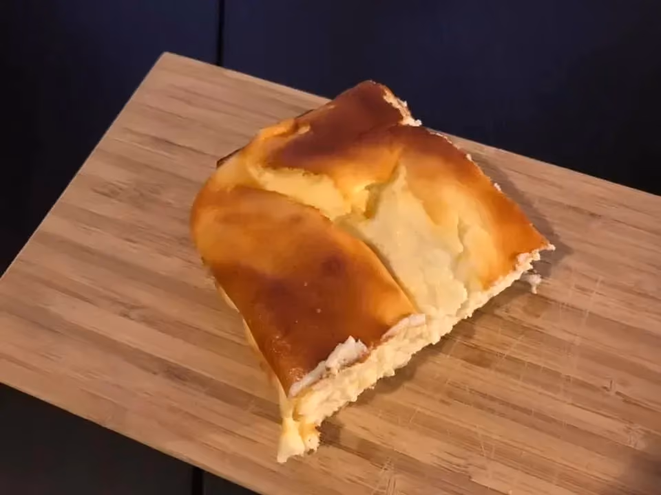 Le gâteau au fromage blanc est présenté sur une grosse pièce de bois rectangulaire. Seule une partie du gâteau subsiste.