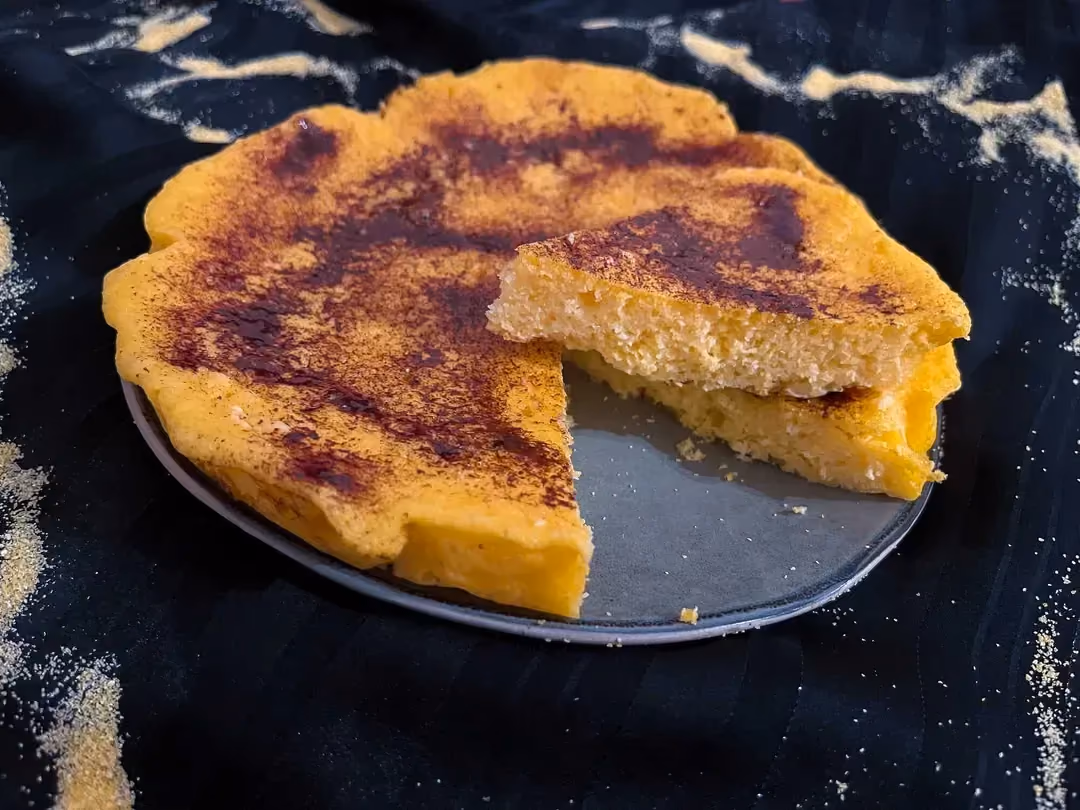 Ce gâteau de semoule à l'orange est présenté sur son plat de cuisson. Une part est coupée et elle est posée sur le reste du gâteau.