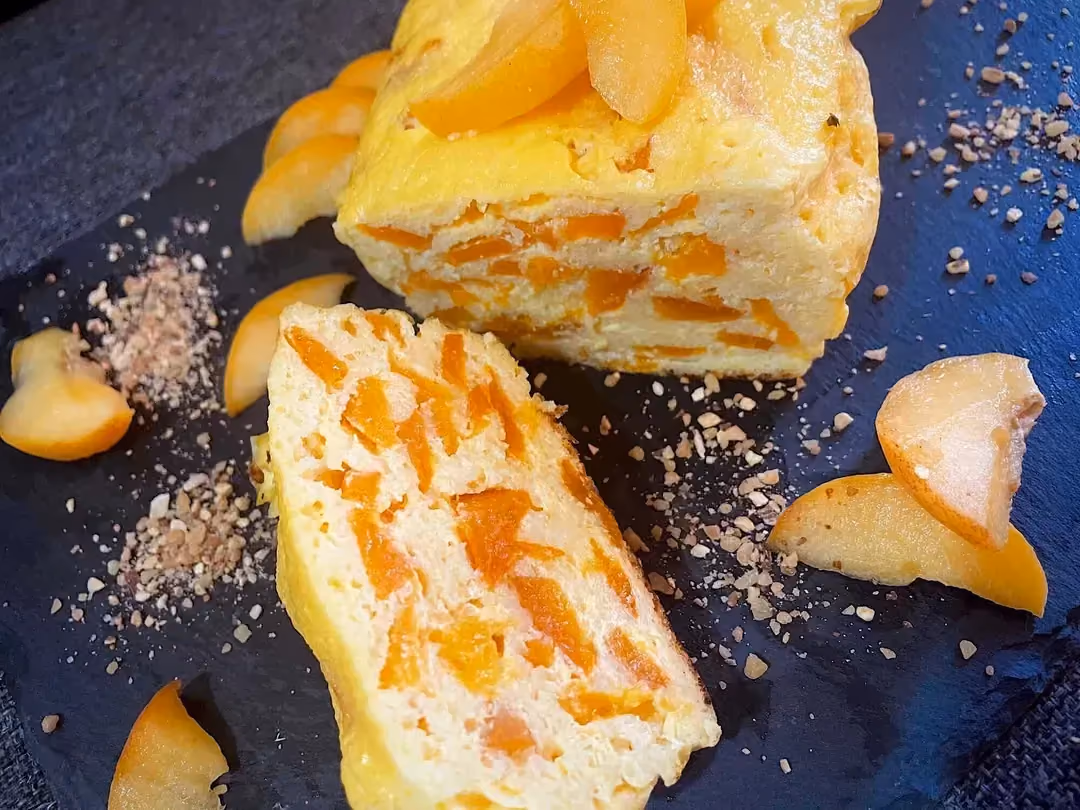 Deux belles parts du gâteau de semoule aux abricots sont présentes sur un plat de couleur noir, elles montrent tout le moelleux de ce dessert.