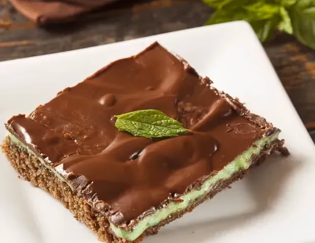 Sur une assiette carrée de couleur blanche se trouve le gâteau façon After Eight avec sa crème de menthe au milieu.