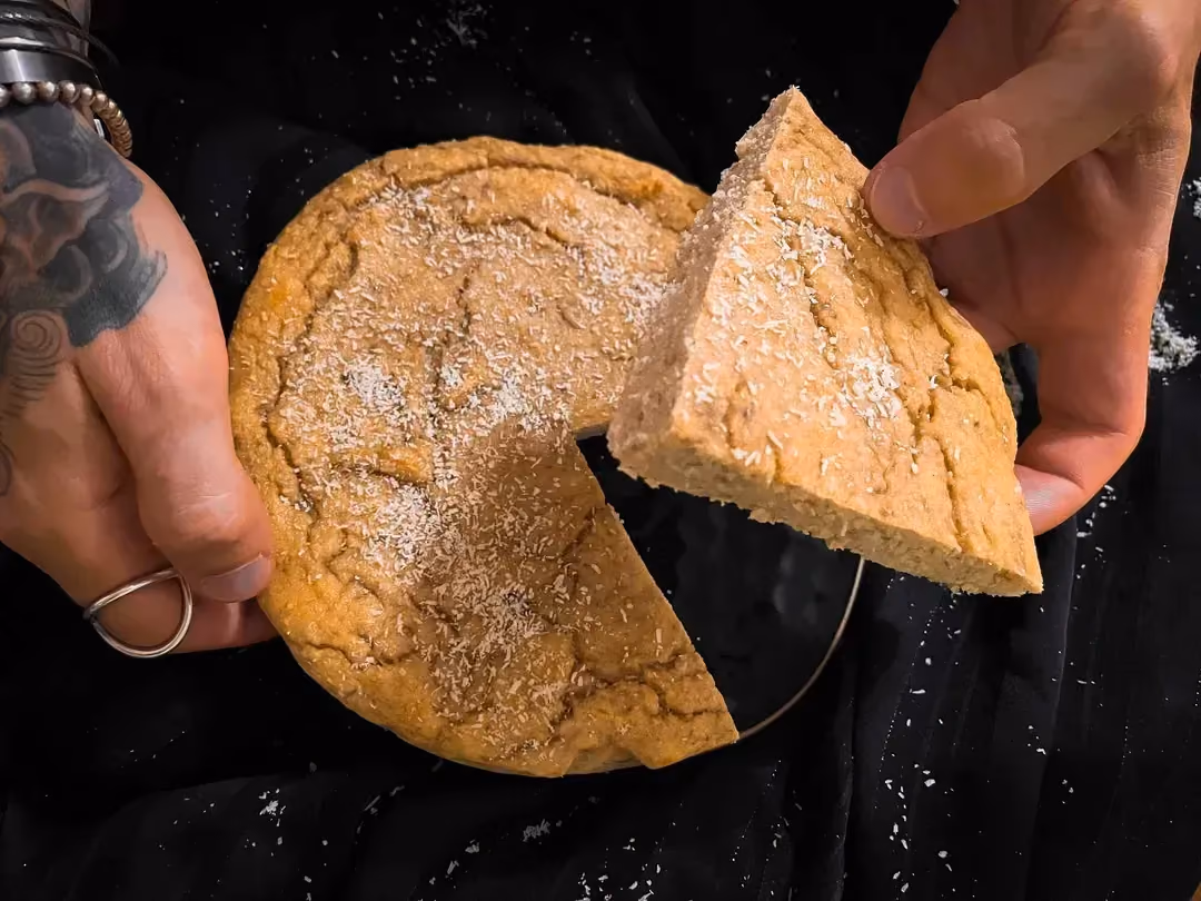 Entre mes mains se trouve un quart de ce gâteau protéiné banane et coco.