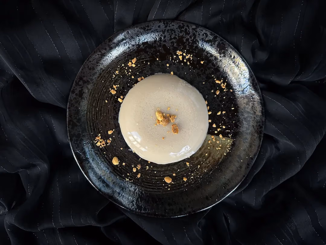 Sur une assiette blanche se trouve une jolie boule de gelée de la taille d'une grosse orange. Au dessus deux amandes sans la peau sont disposées.