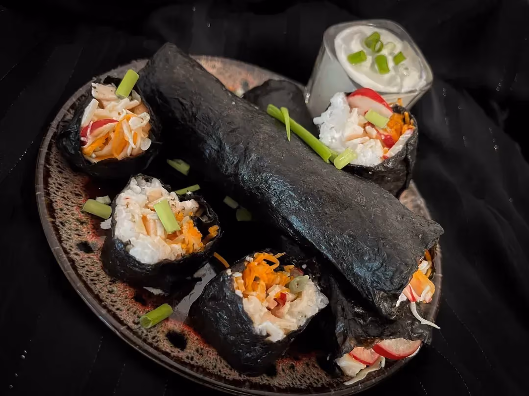 Four large bites are wrapped in nori seaweed, made with rice, turkey breast, radish, grated carrot, and peanut sauce.
