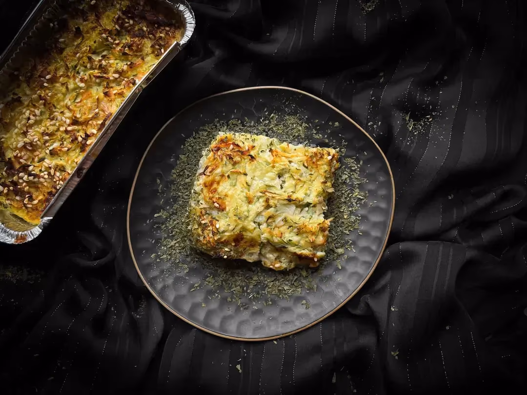 In a small blue textured bowl, there is a serving of zucchini, rice, and turkey breast gratin