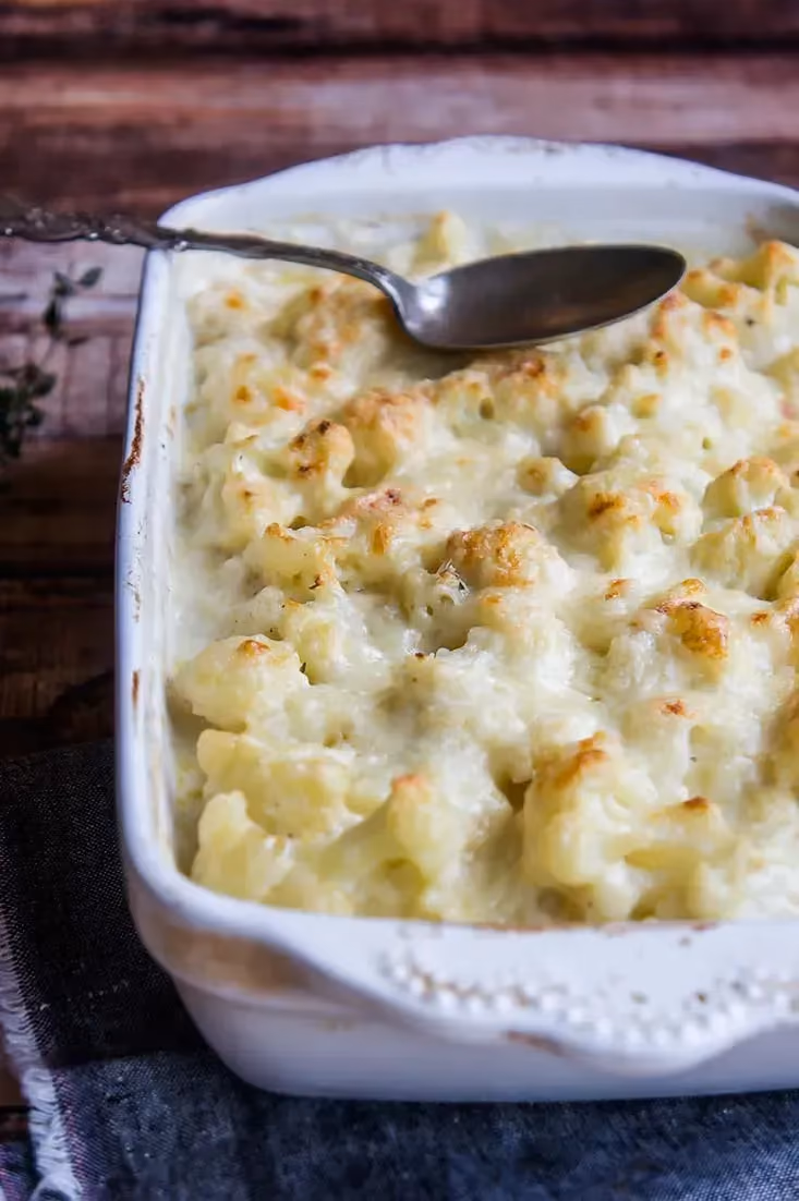In a white rectangular dish, the cauliflower gratin looks perfectly tender. It is lightly browned on top.