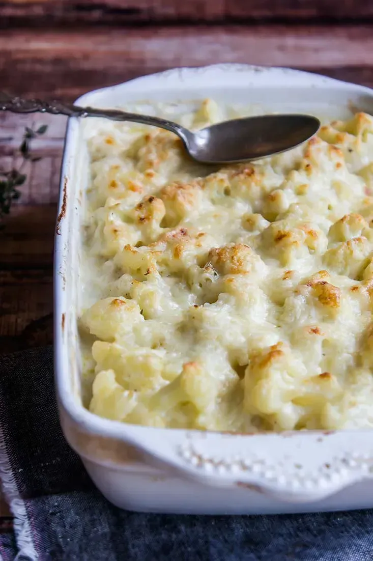 In a white rectangular dish, the cauliflower gratin looks perfectly tender. It is lightly browned on top.