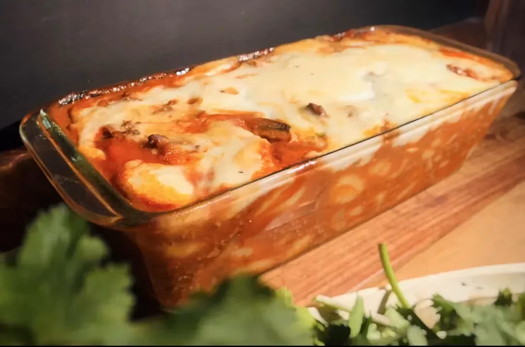 In a transparent baking dish, the meat and gnocchi have taken on the color of the tomatoes. On top, the grated cheese is beautifully browned.