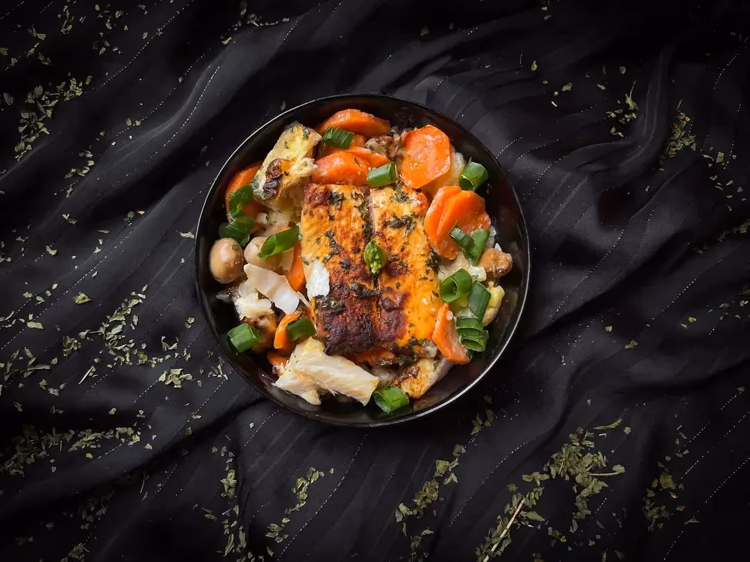 Dans un gros bol se trouve le gratin marin composé de filets de saumon et de colin avec des carottes, du choux fleur et des champignons de Paris.