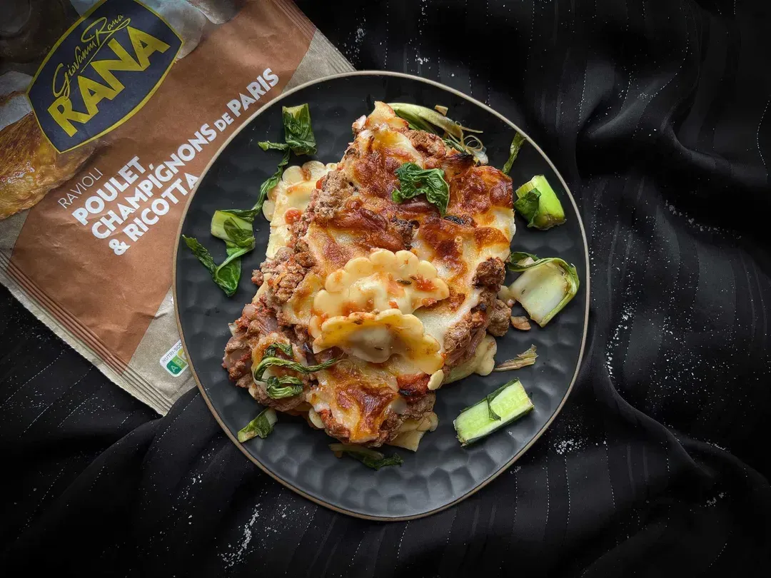 In a small blue textured bowl is the ham ravioli gratin.