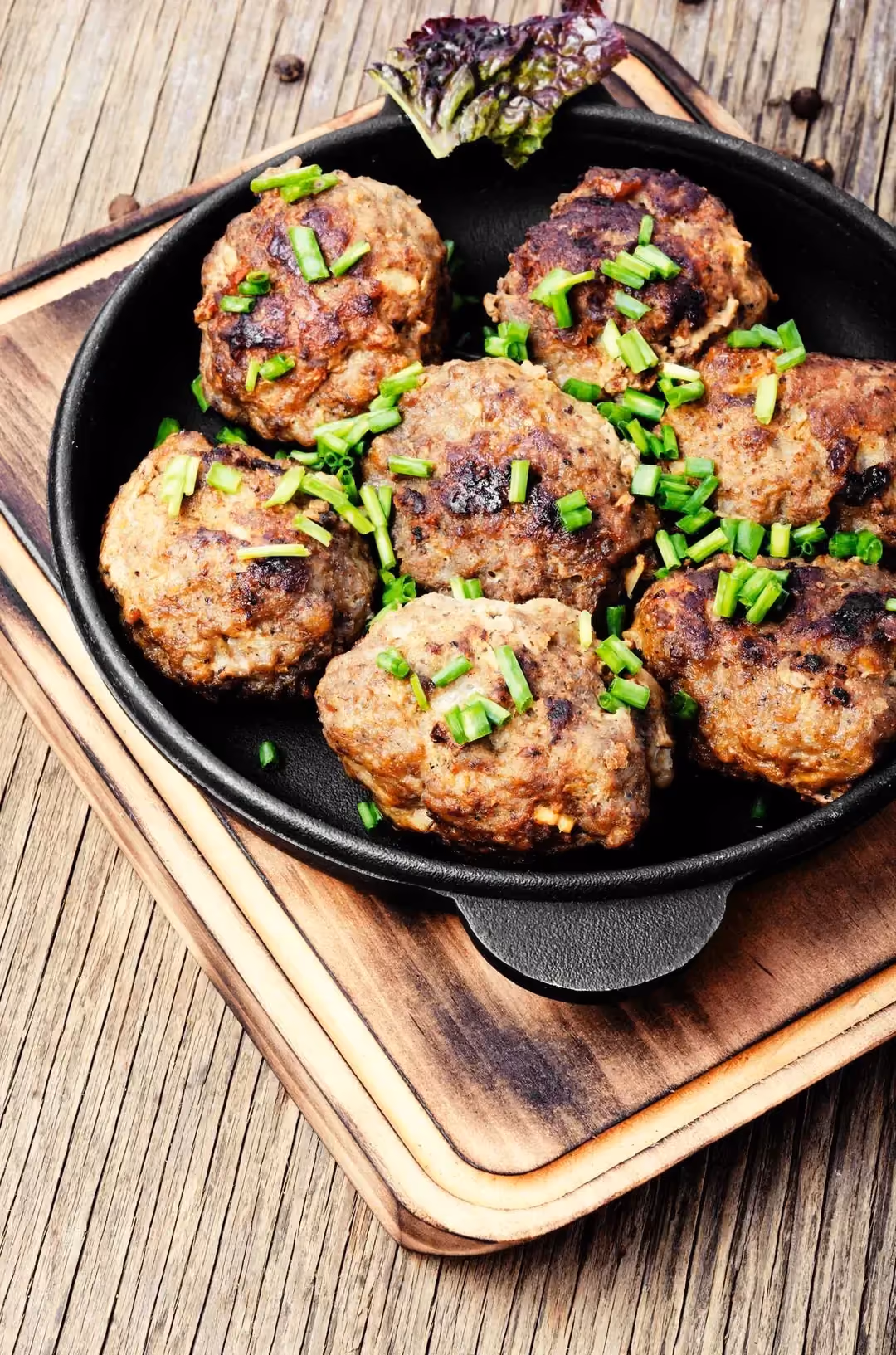 Présentées dans le plat de cuisson, sept boulettes de viande de porc bien dorées sont parsemées de ciboulette finement ciselée.