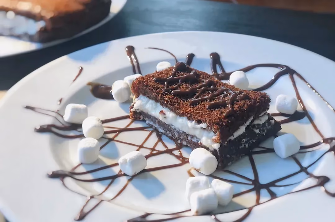 Sur une assiette de blanche, se trouve une jolie tranche de ce dessert avec entre deux couches de chocolat la préparation à base d'amandes.