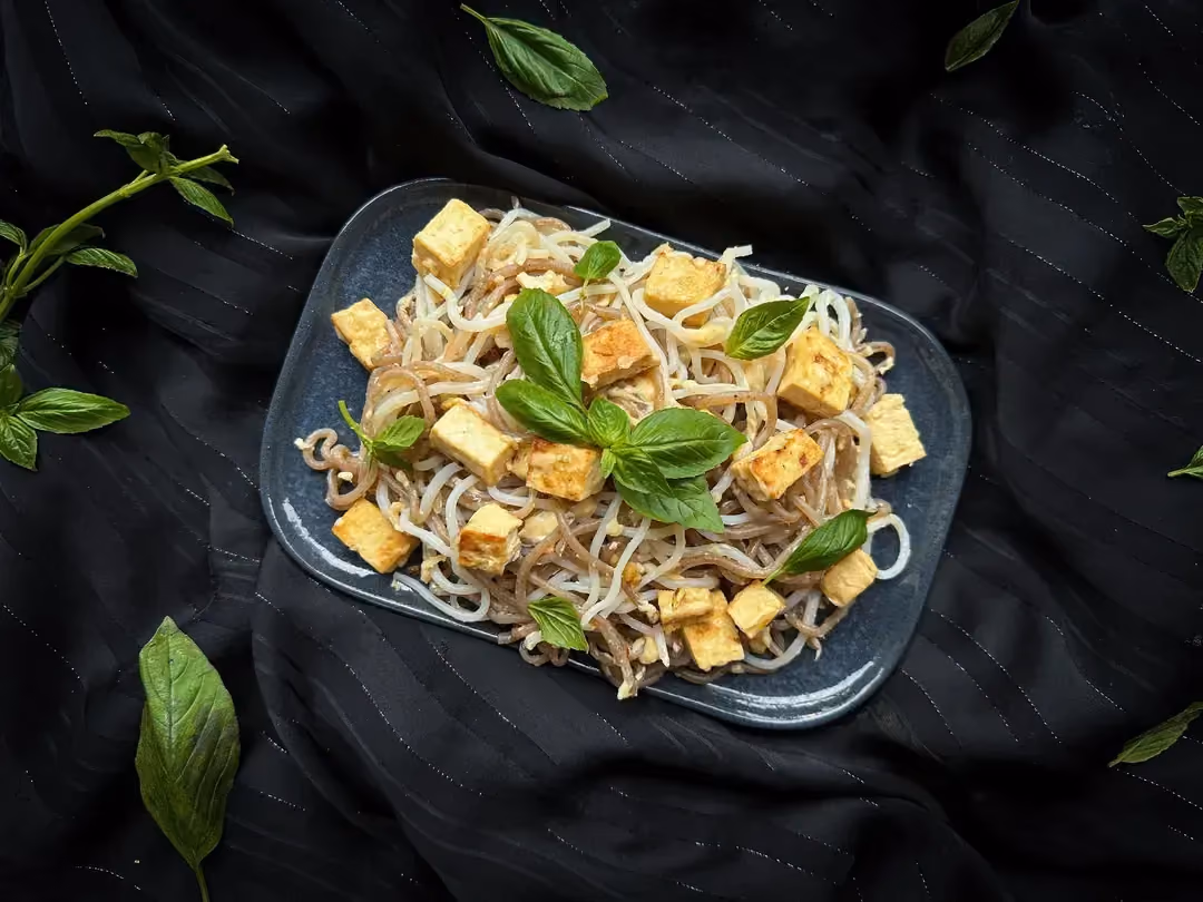 A shallow rectangular earthenware dish with rounded edges is used to present the garlic konjac recipe with tofu and parmesan.