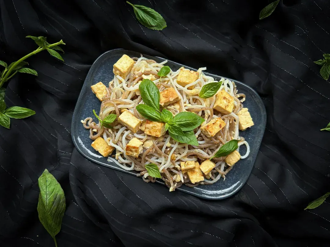 A shallow rectangular earthenware dish with rounded edges is used to present the garlic konjac recipe with tofu and parmesan.