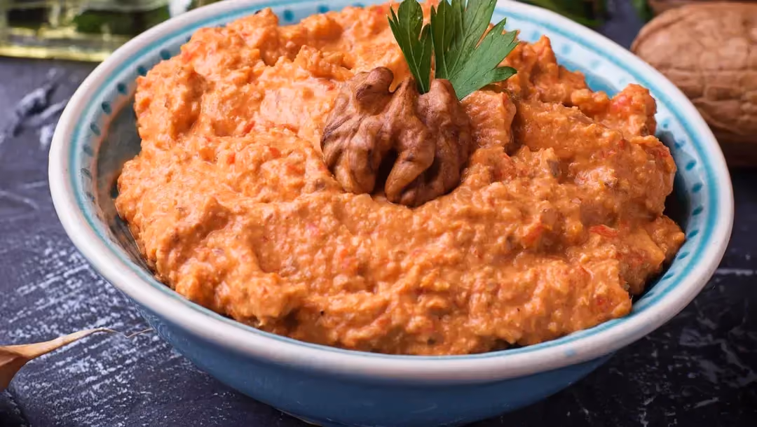 Dans un large bol de couleur bleu et blanc se trouve la pâte à tartiner prénommée Ktipiti. La belle couleur orange est donnée par le paprika.