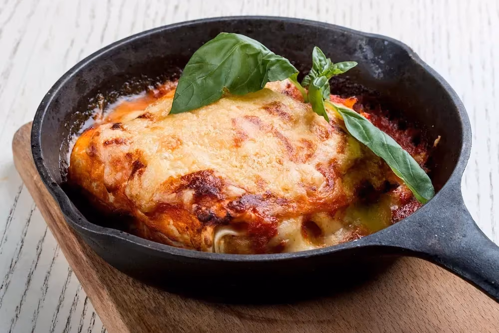 Dans une poêle on trouve les lasagnes. Quelques petites feuilles de basilic sont déposées dessus.