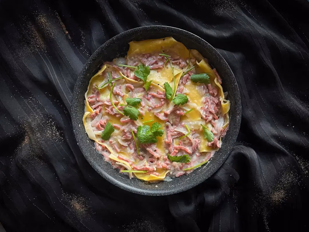 Les lasagnes aux allumettes de bacon, oignons et sauce béchamel sont présentés dans un saladier de couleur bleu.