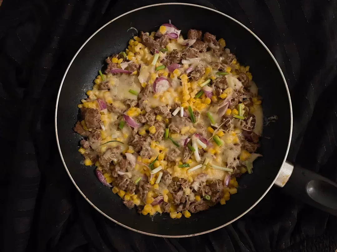 In a nonstick skillet, there is the very cheesy corn and beef, all mixed together.