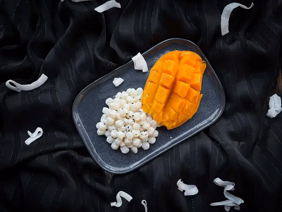 The recipe is presented in a white oval shallow dish. The konjac pearls are covered with beautiful slices of mango.