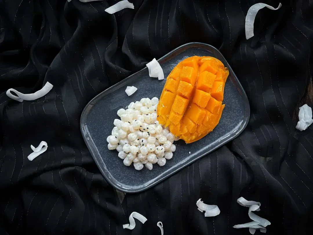 The recipe is presented in a white oval shallow dish. The konjac pearls are covered with beautiful slices of mango.