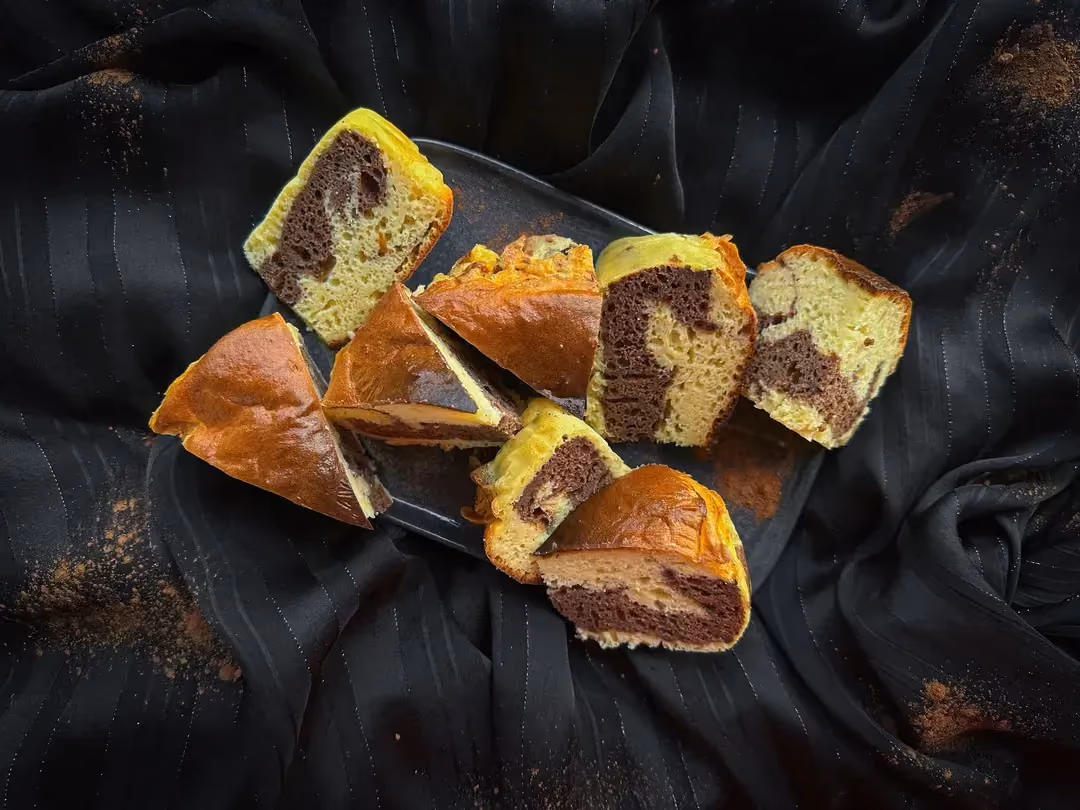 Sur trois assiettes blanches superposées, se trouve trois tranches de marbré au chocolat protéiné. Le topping est assuré avec deux belles mûres.