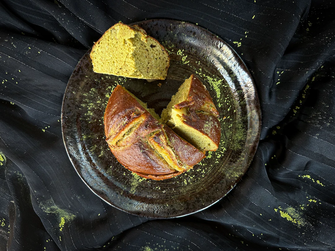 The protein matcha banana bread is presented in a ceramic bowl. It is cut into three pieces.