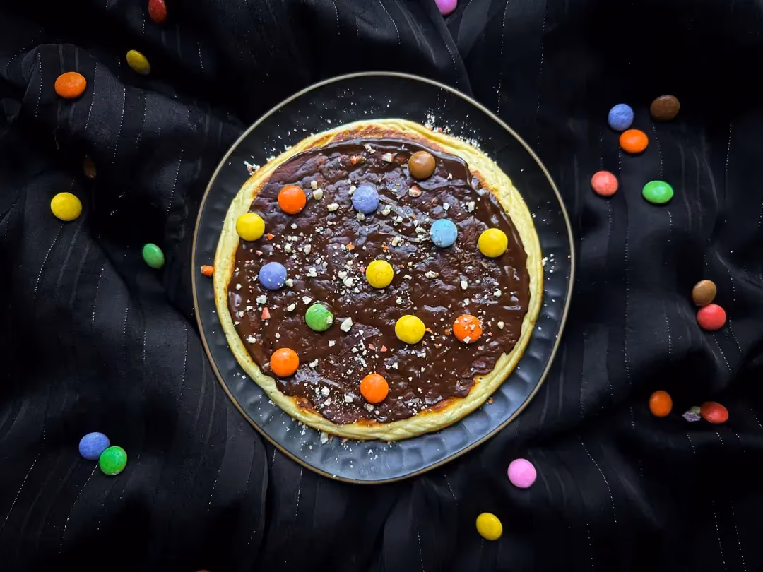 Sur le dessus de l'épais pancake sont disposés les smarties. Des tranches de kiwi et des quartiers de mandarine sont présents.