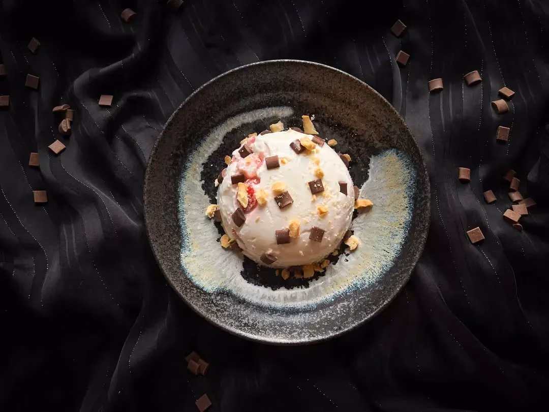 Le maxi pudding fromage blanc, fraises et pépites de chocolat est présenté dans un petit saladier de couleur bleu.