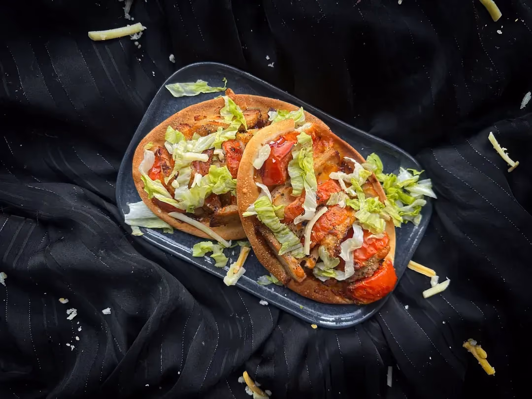 Les trois pizzas au poulet, sauce tomate et fromage sont présentées sur un plateau en bois et décorées d'oignons verts.