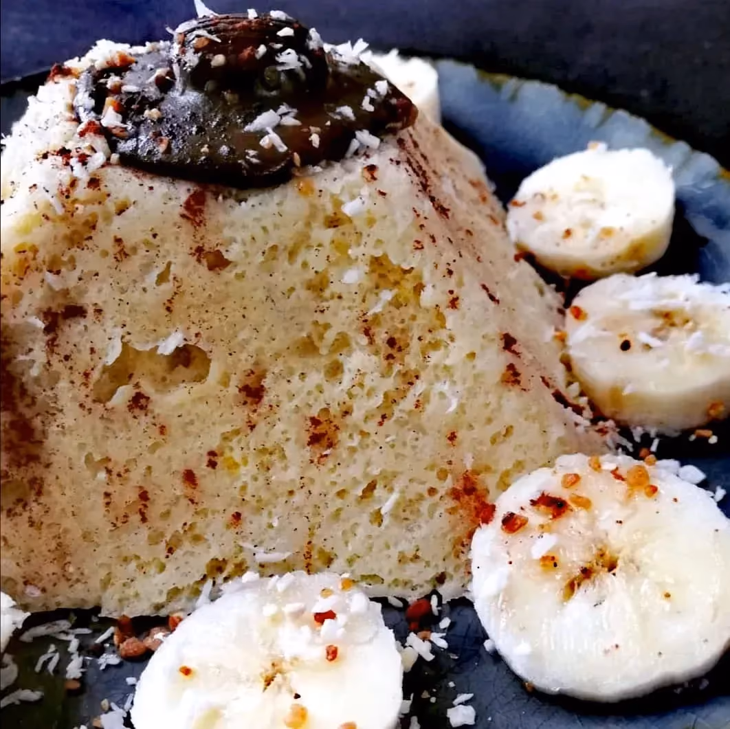 Le minute cake est en forme de pyramide avec un coulis de chocolat comme topping. De généreuses tranches de noix de coco sont disposée tout autour.